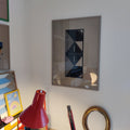 Art deco mask wall art in black linoleum on cardboard, framed on wall — original by Lisa Ketty