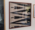 Abstract art piece with geometric shapes in a wooden frame on a wall.