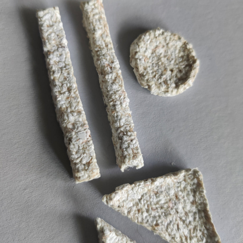 Three pieces of paper pulp on a gray surface