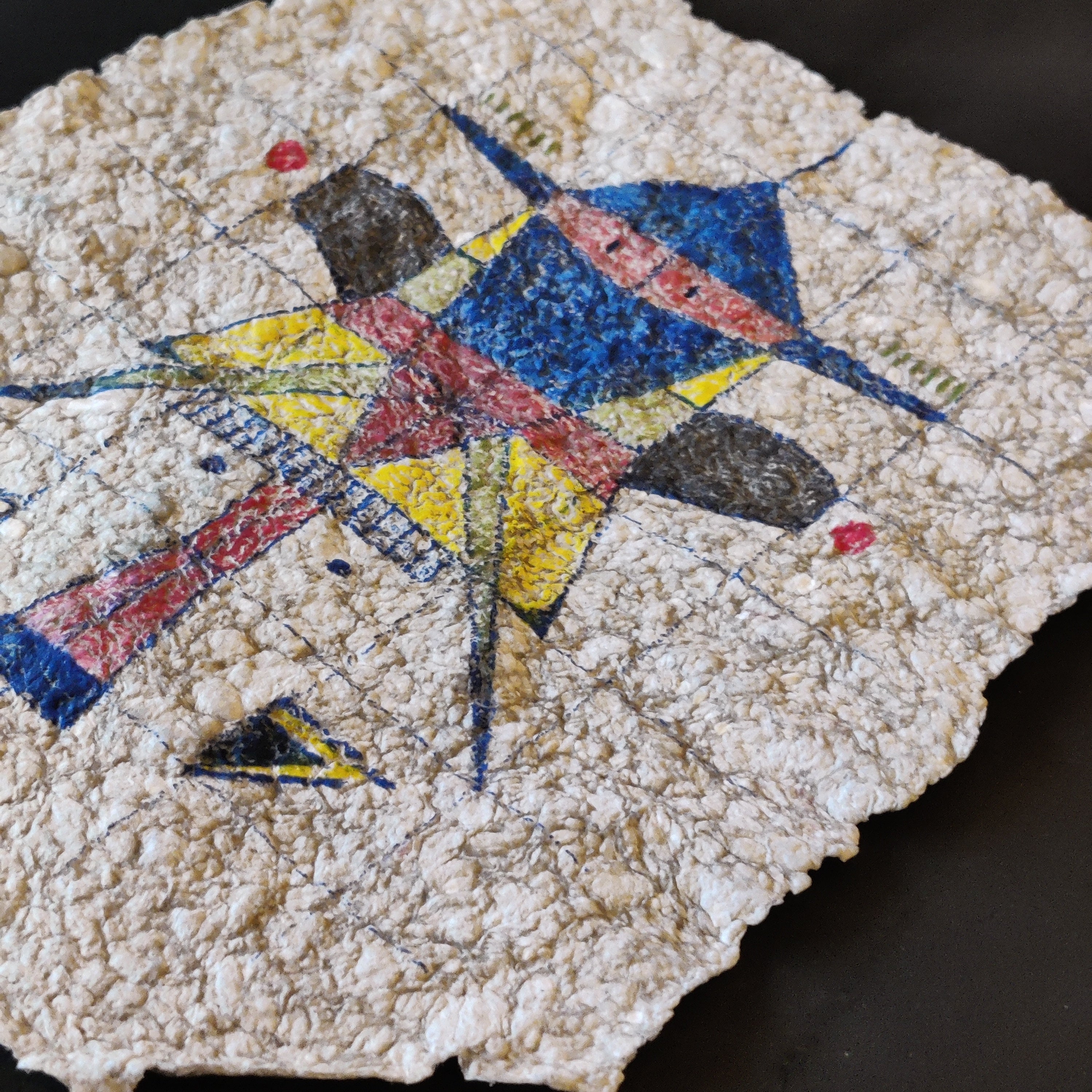 Mosaic artwork on paper pulp with geometric shapes in red, blue, and yellow formed as a rocket man

