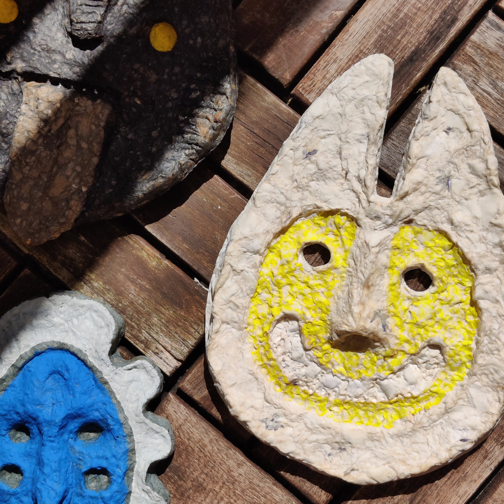 Decorative stone faces with yellow and blue designs on a wooden surface
