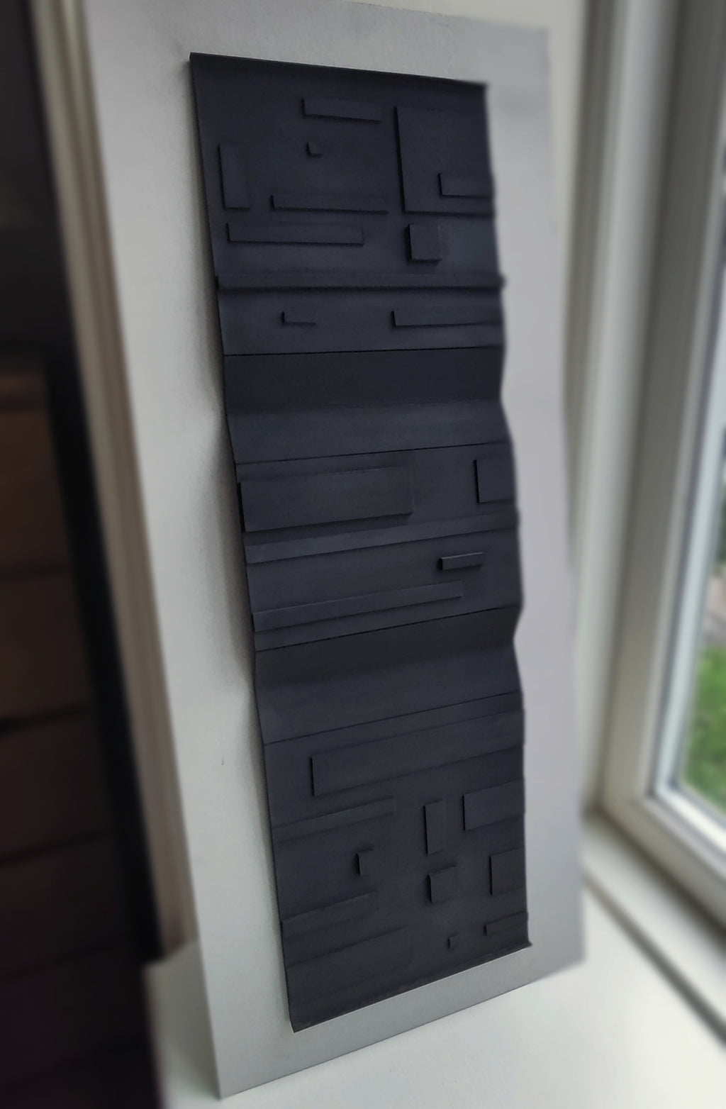 Black textured panel on a white wall next to window