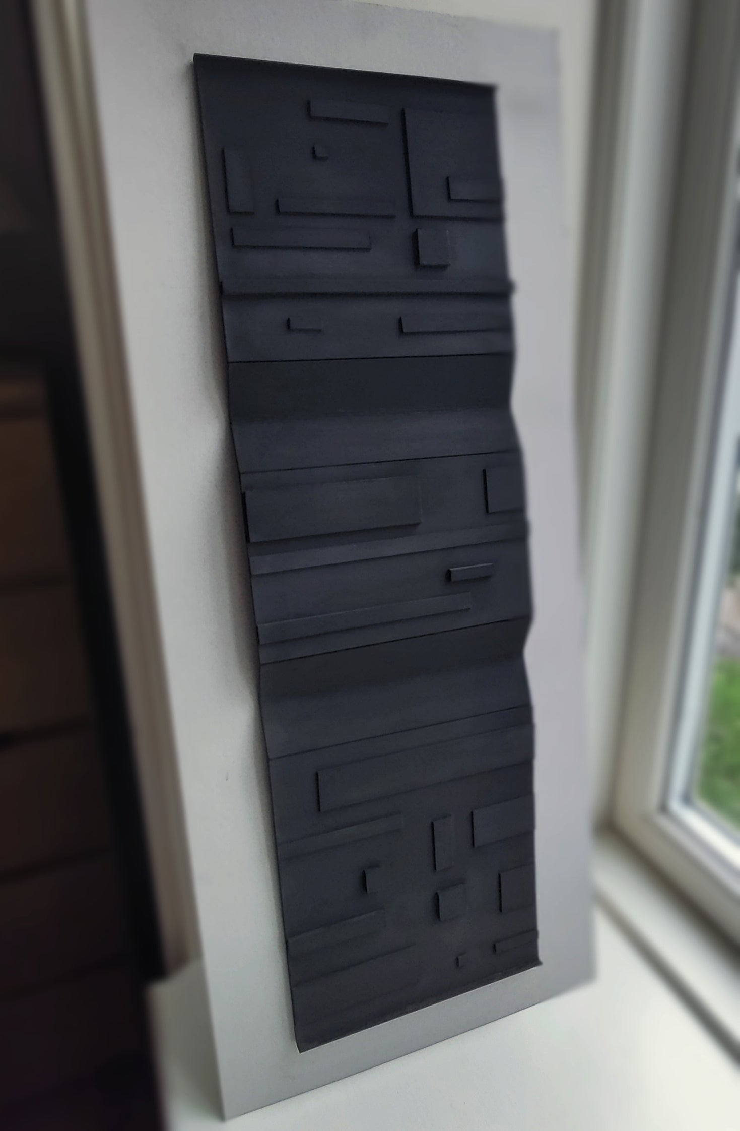 Black textured panel on a white wall next to window