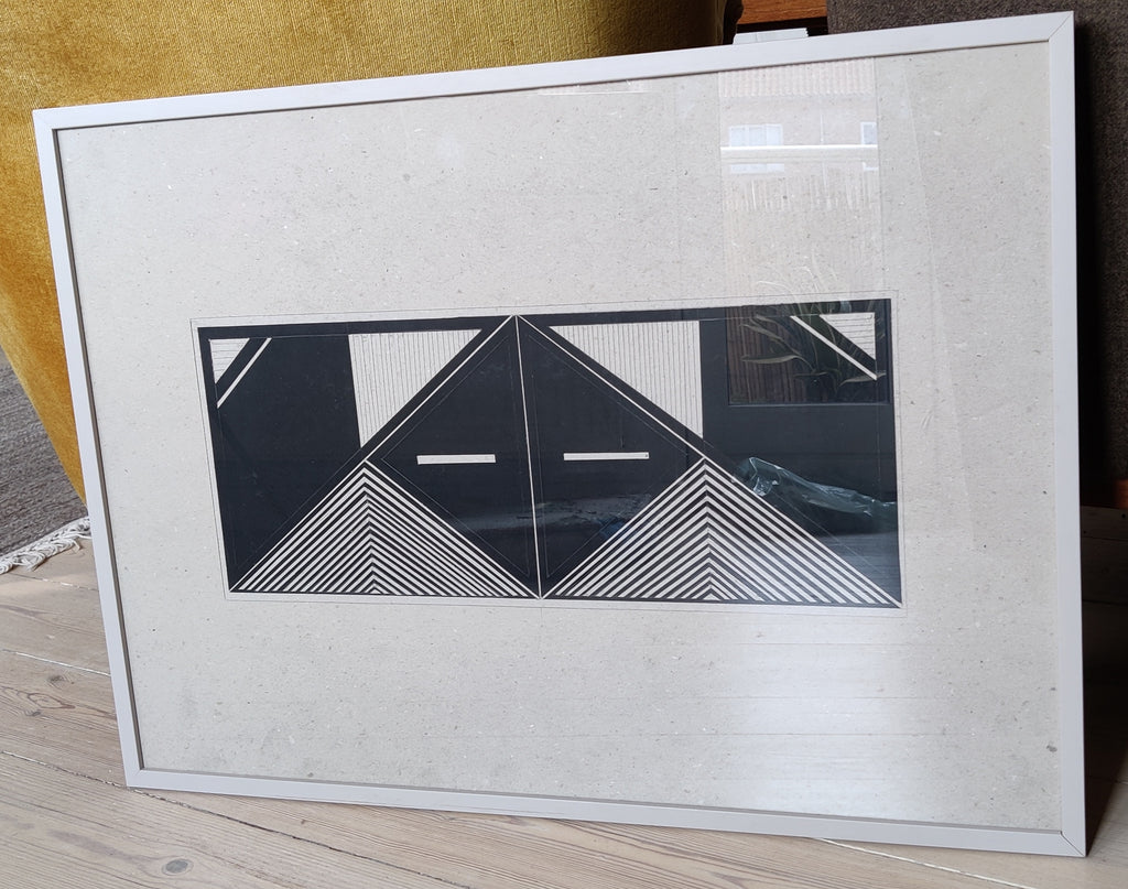 Symmetrical geometric mask art painted black on cardboard, framed front view