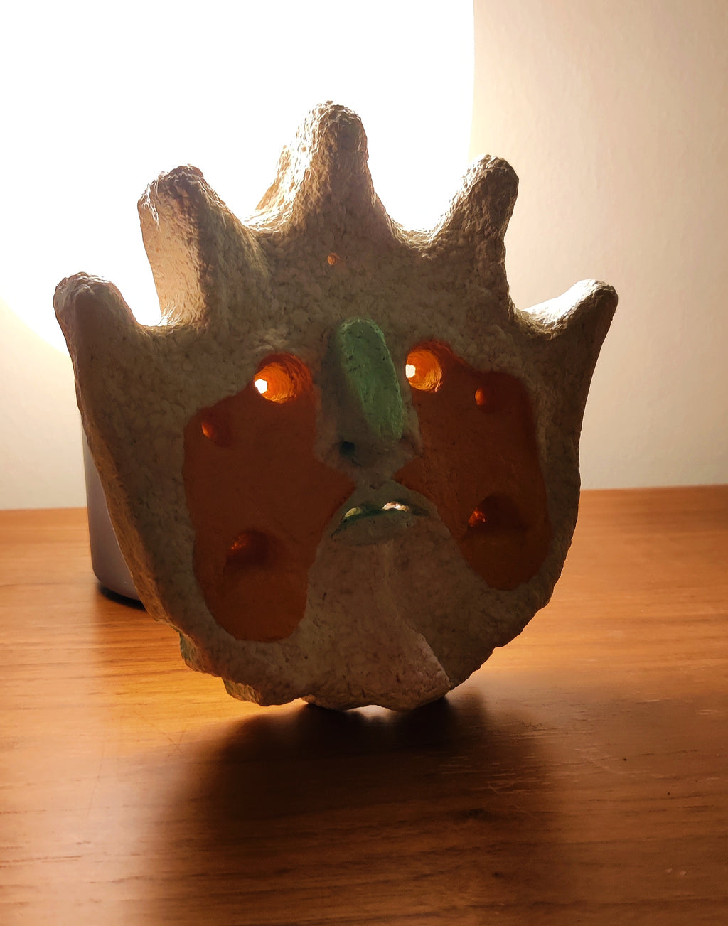 The Sun King Paper pulp wall art sitting with a backlight to show the eyes.