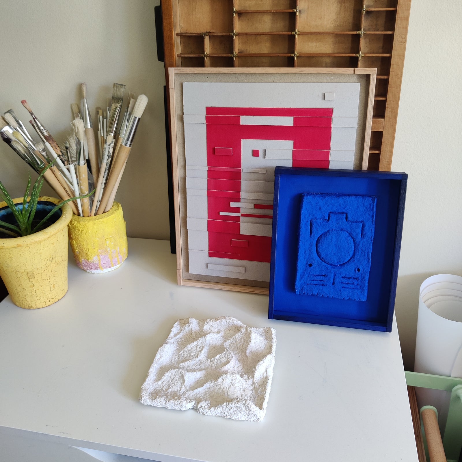 Red, blue and white relief artworks by Lisa Ketty on a wall